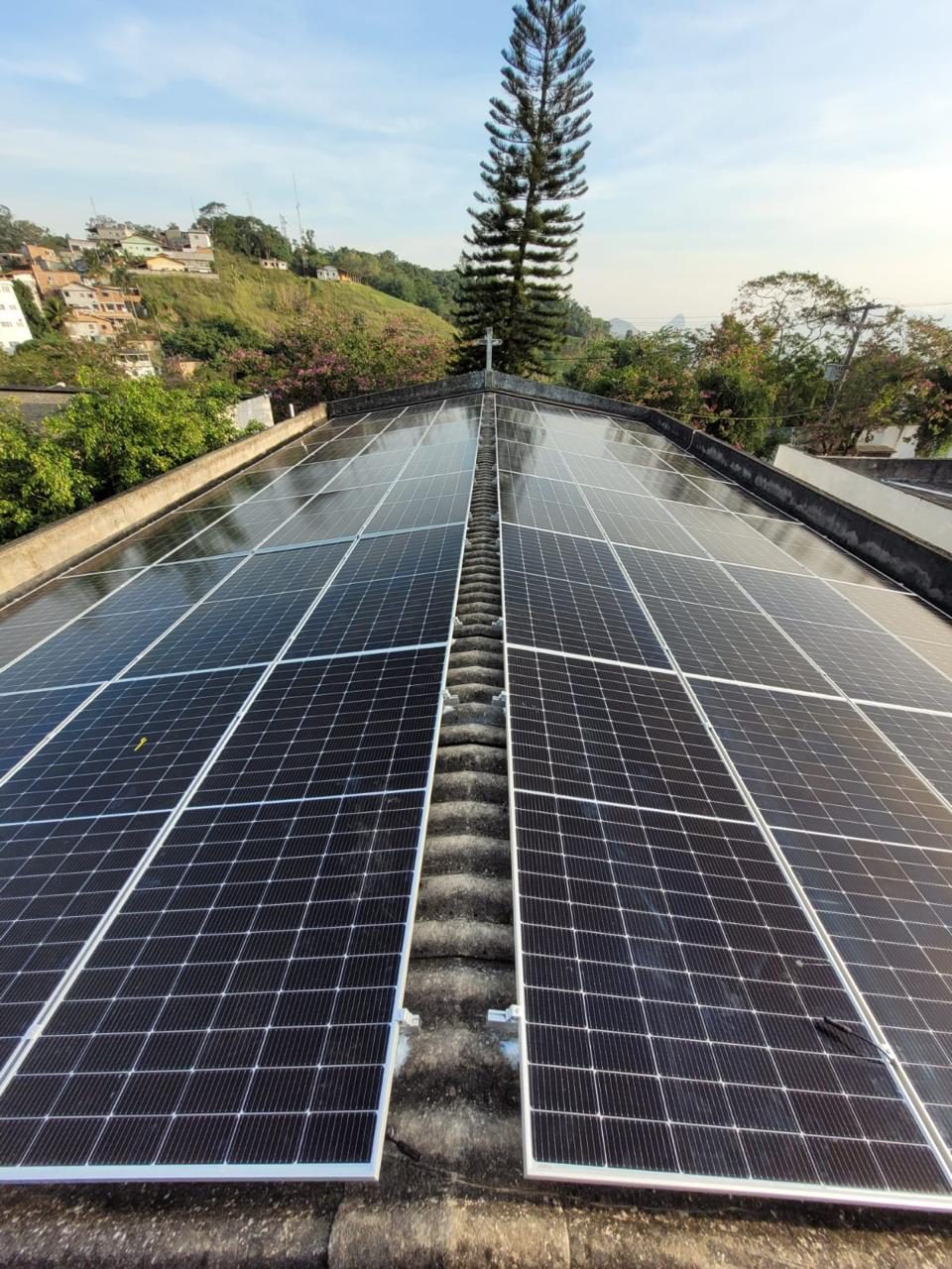 Painéis solares em telhado residencial cercado de vegetação